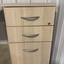Wooden file cabinet with three drawers and metal handles.